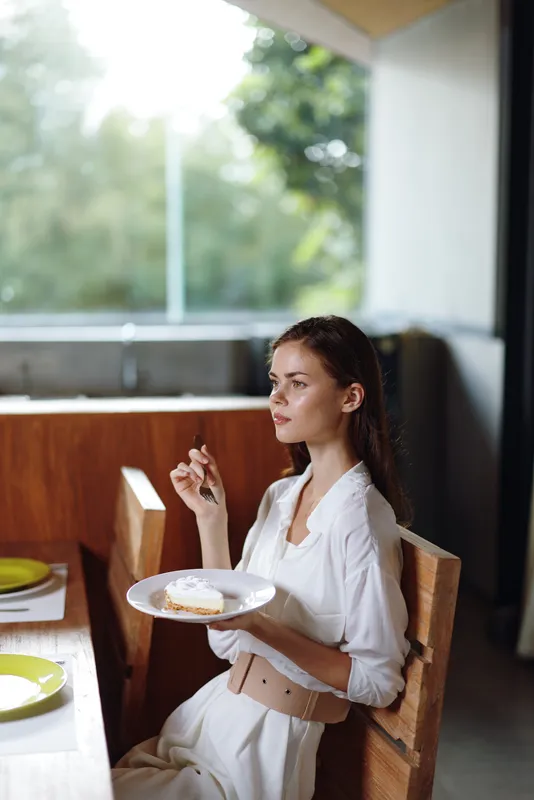 Счастливая женщина наслаждается романтическим ужином дома с вкусным тортом и вином