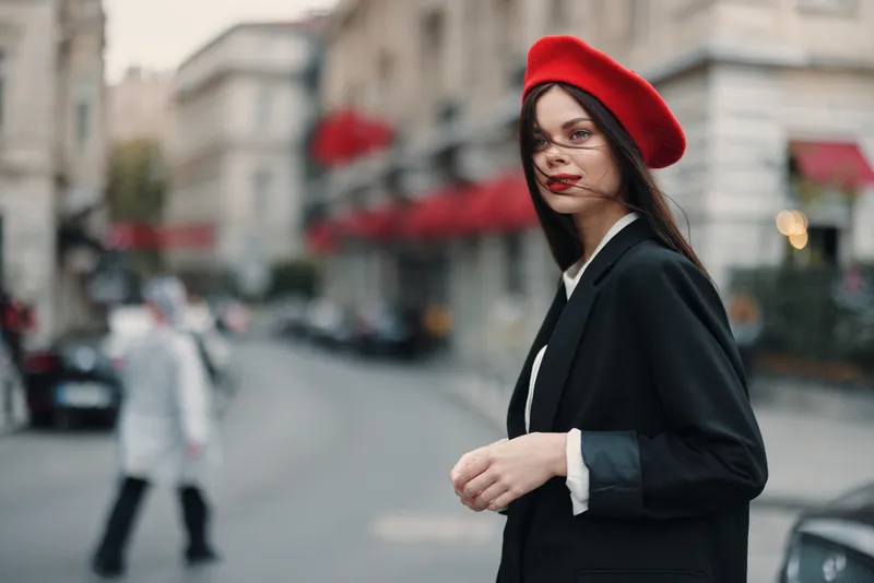 Портрет модной женщины на улице на фоне города в стильной одежде, с красными губами и красным беретом
