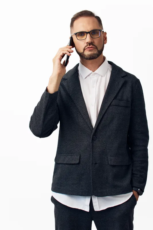A businessman on a phone, professional and confident, captured against an isolated colored background. Subtle emotion shows focus, determination, and readiness for strategic dialogue.