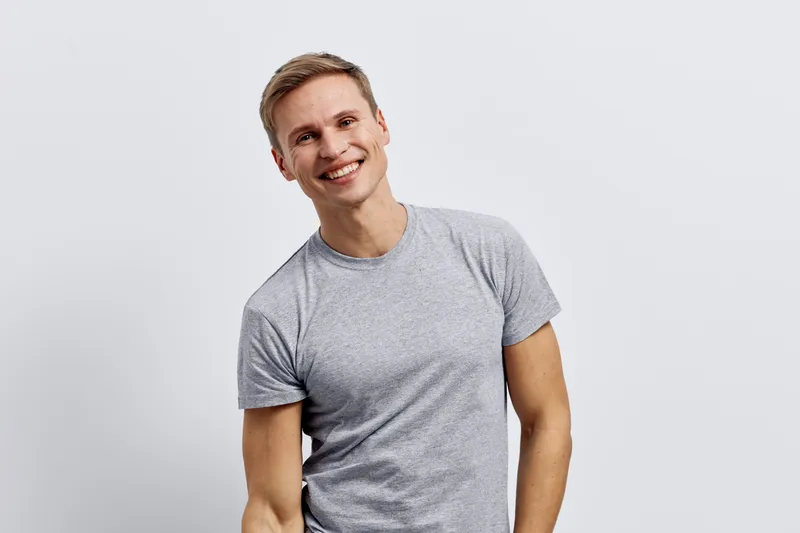 Cheerful smiling man with short light brown hair wearing casual gray t-shirt isolated on plain white background studio portrait. People lifestyle concept