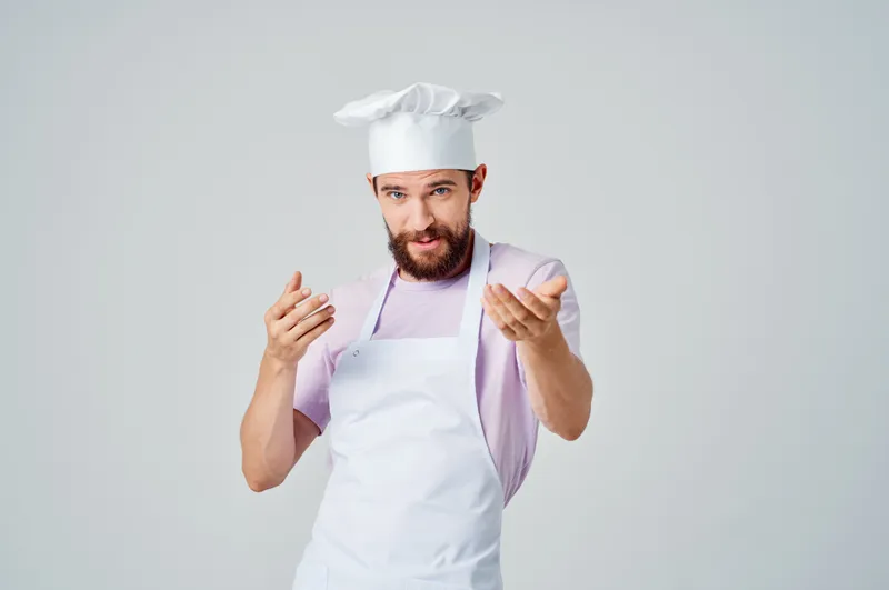 Эмоциональный шеф-повар жестикулирует руками, занимаясь профессиональным приготовлением изысканных блюд