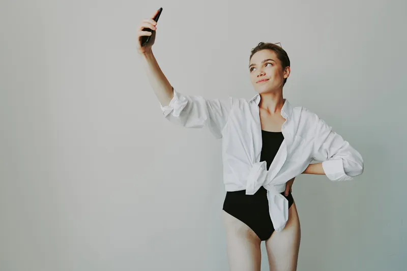 Девочка-подросток, блогер, фотографирует и снимает себя на видео на свой телефон для контента в социальных сетях