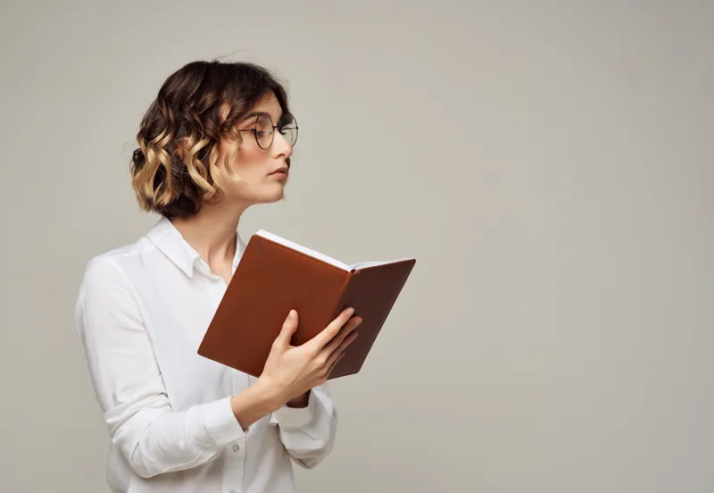 Женщина с кудрявыми волосами в очках с книгой в руках, работа в студии