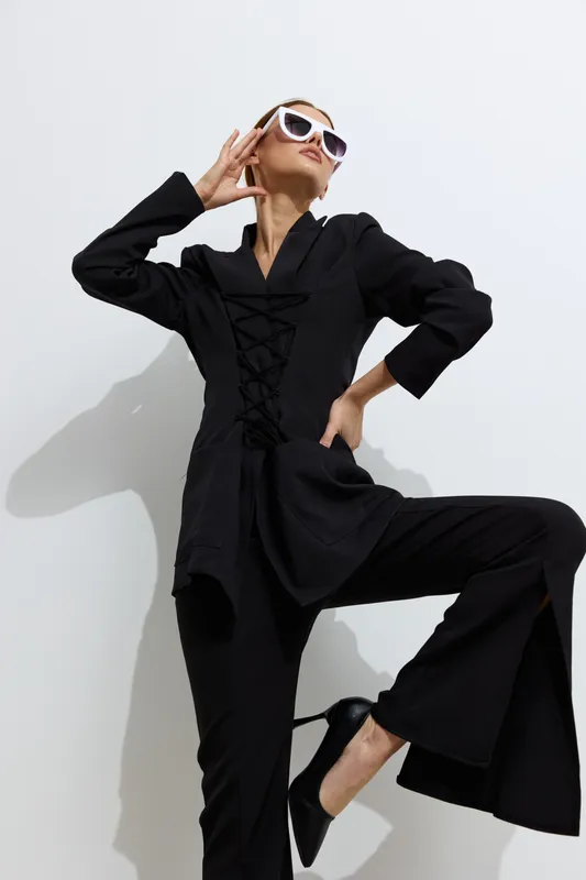 Fashion woman in black stylish outfit and white sunglasses posing confidently against white background, highlighting contemporary beauty and elegance in urban style.