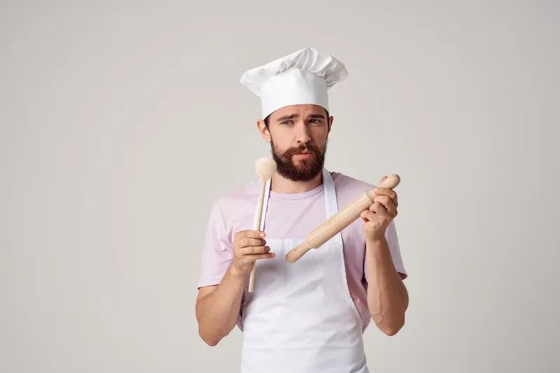 Шеф-повар в колпаке пробует еду на вкус, профессиональное приготовление пищи