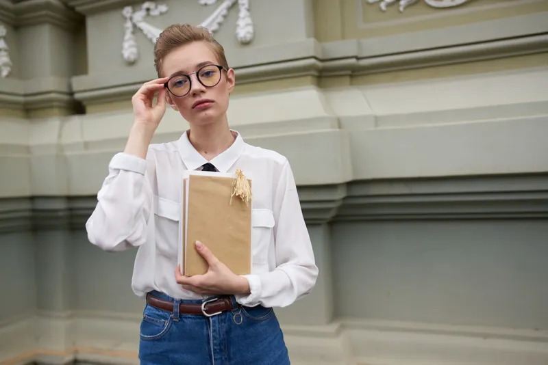 Короткостриженая женщина с книгой в руках на открытом воздухе, чтение, образование
