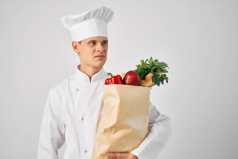 Мужчина в поварской форме держит упаковку продуктов