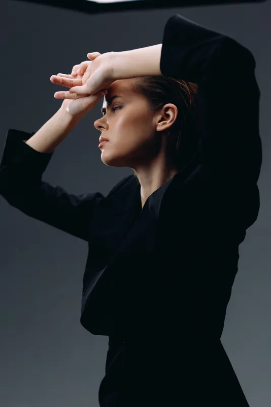 Profile of a young woman in black clothing with a thoughtful expression and muted background, showing elegance and contemplation.