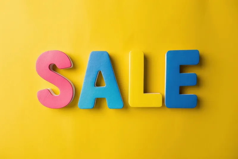 Плоская композиция с разноцветными деревянными буквами sale на желтом фоне