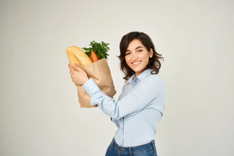 Жизнерадостная женщина с пакетом продуктов в супермаркете, шопинг, образ жизни