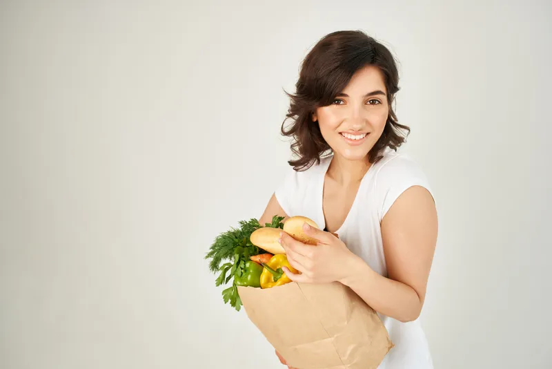 Весёлая женщина с пакетом продуктов из супермаркета — полезная еда