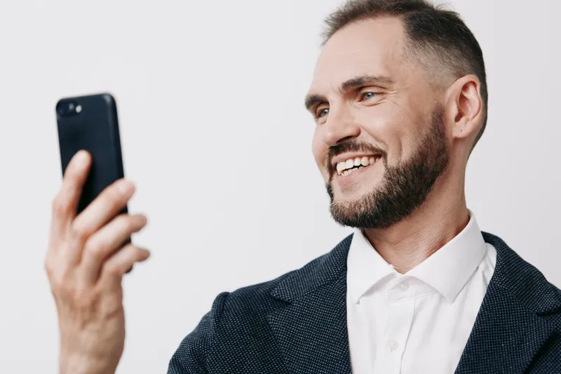 A confident business professional takes a selfie against a solid colored background, showcasing approachable charm, modern work life, and a positive, ready-to-connect mindset.