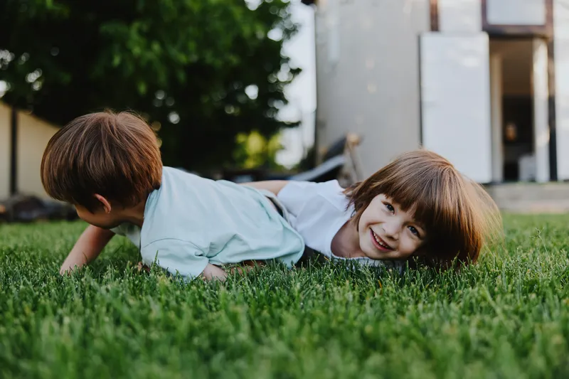 Playful children enjoying a sunny day outdoors, smiling happily on the green grass. Their laughter fills the air, creating a joyful atmosphere of childhood fun.