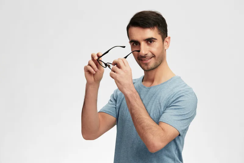 Весёлый мужчина в очках и повседневной одежде, выражающий эмоции, кадр обрезан