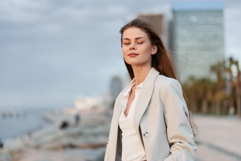 Confident woman in light gray business suit outdoors with modern city background and calm expression, showcasing professionalism and empowerment