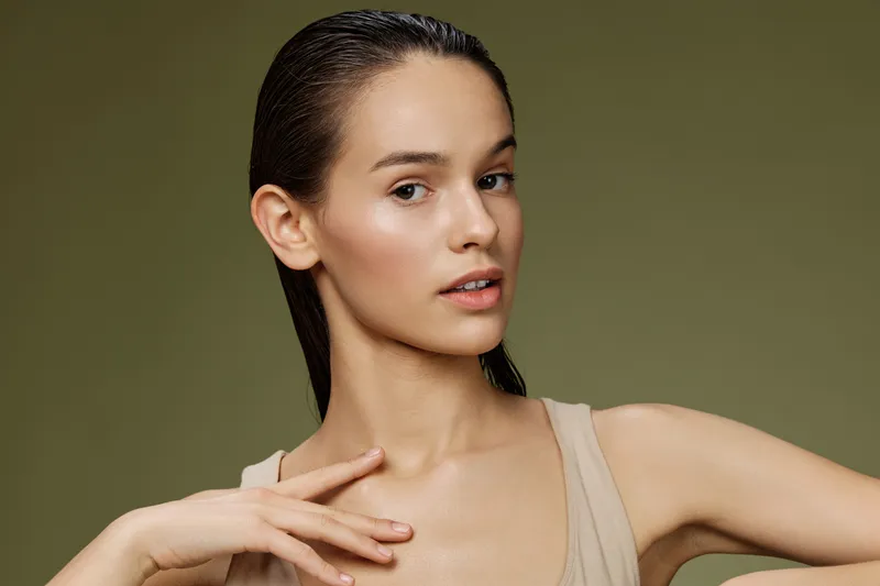 Natural beauty portrait of a young woman with wet hair, showcasing healthy skin and a neutral color palette, ideal for beauty and skincare concepts