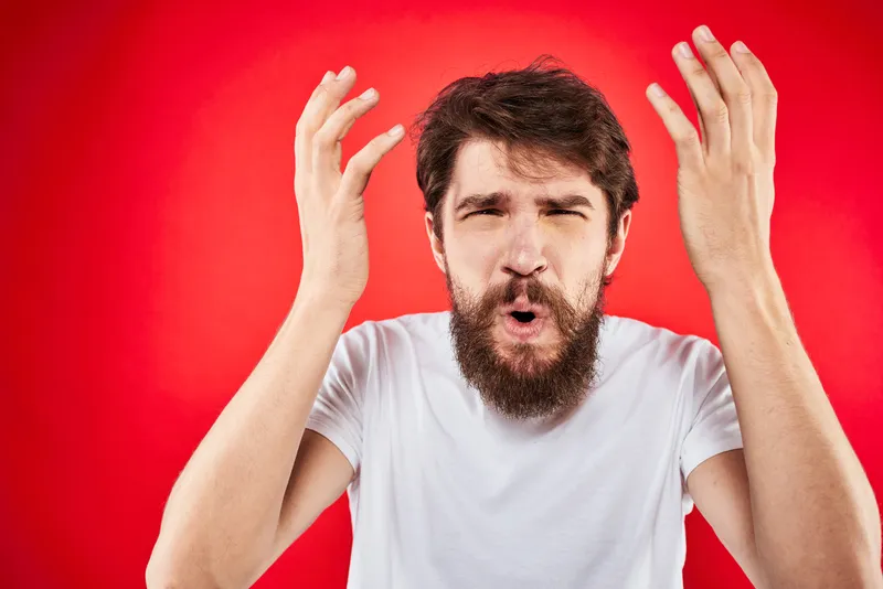 Бородатый мужчина жестикулирует руками, на нём белая футболка