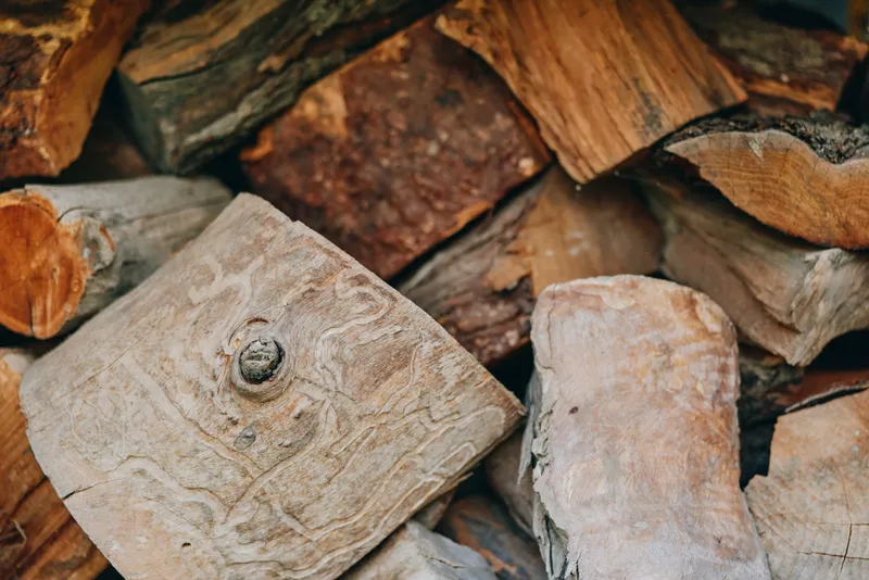 firewood stacked logs woodpile closeup texture rustic: close-up of seasoned split firewood and bark in a rural woodpile, autumn farmhouse atmosphere for fireplace, camping and cozy lifestyle scenes.