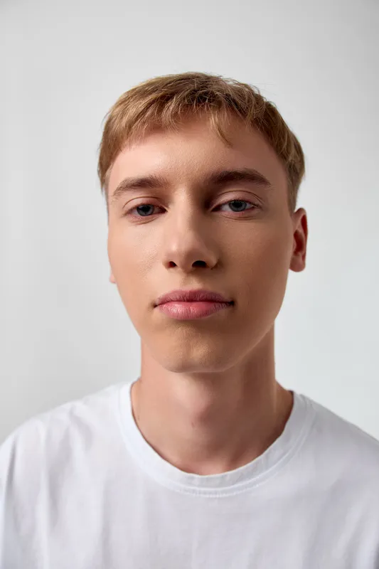 Close up of a young man in a white shirt against a neutral background, studio lighting with calm expression, clean and versatile stock focus