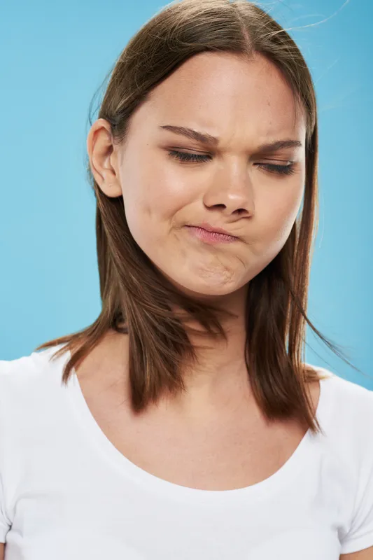 Женщина на синем фоне с закрытыми глазами, эмоция модели — недоумение