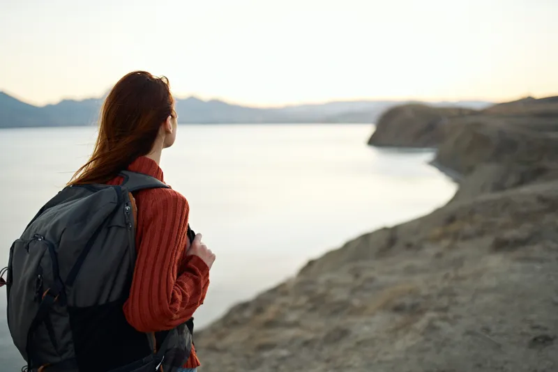 Женщина путешествует в горах на открытом воздухе рядом с морем