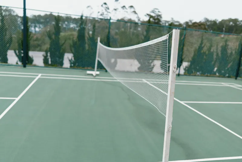 Empty tennis court with net and green surface, ideal for training and leisure activities, showcasing outdoor sports and fitness lifestyle