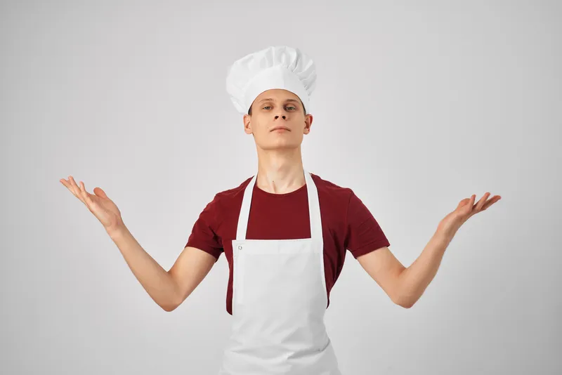 Мужчина-повар в униформе работает на кухне ресторана, занимаясь приготовлением пищи