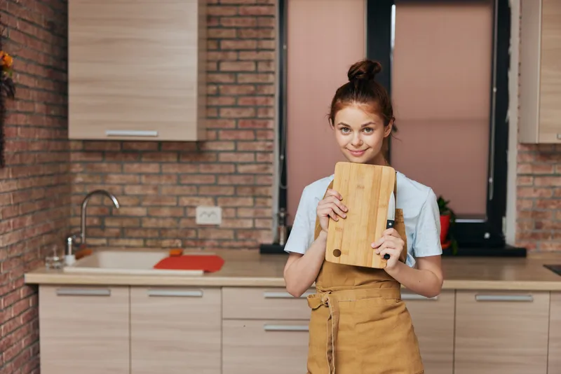 Женщина на кухне нарезает продукты на разделочной доске ножом