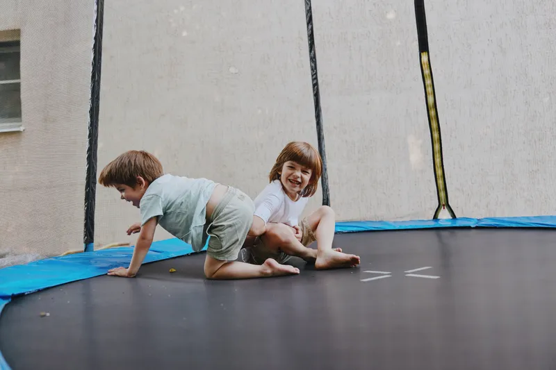Happy children playing on a trampoline, enjoying a sunny day while laughing and smiling together. Their joy captures the essence of childhood fun and adventure.