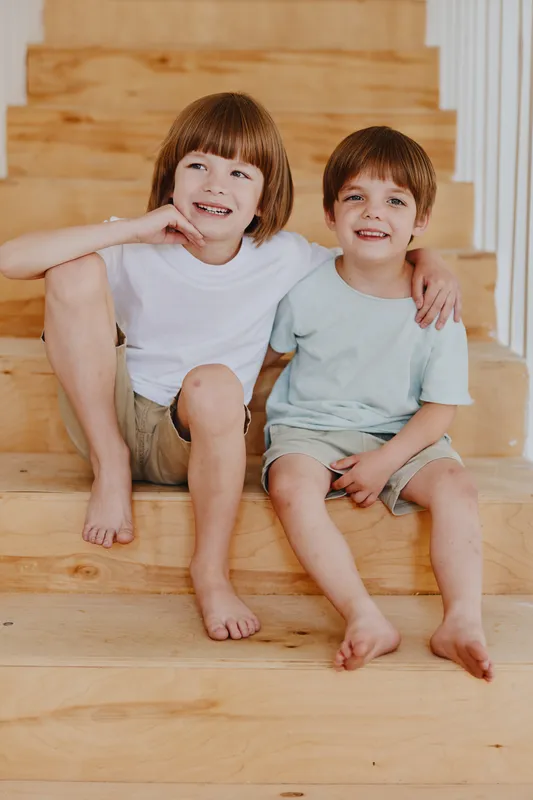 Happy children sitting on wooden stairs, enjoying their time together with friendly smiles and relaxed expressions, showcasing childhood joy and innocence.