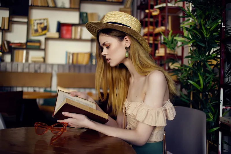 Весёлая женщина читает книгу в кафе, общаясь
