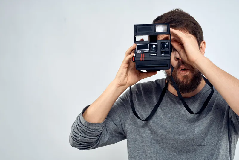 Фотограф профессионально работает в креативной технологии, создавая снимки в стиле папарацци на светлом фоне