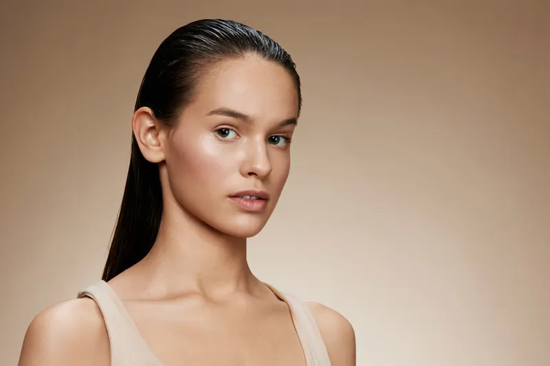 Portrait of a young woman with straight hair showcasing natural beauty, neutral clothing, and a soft expression ideal for beauty and wellness themes