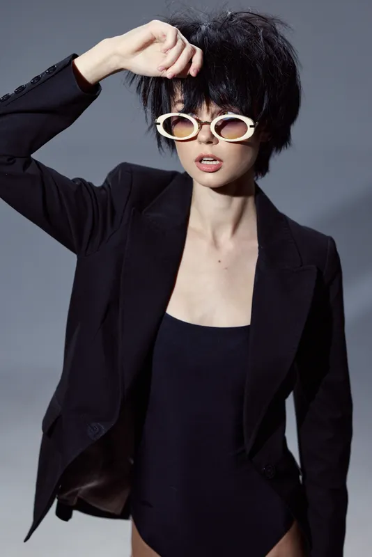 stylish woman wearing black blazer and unique sunglasses with short hair in modern fashion look