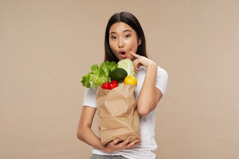 Женщина азиатской внешности с сумкой продуктов, домохозяйка, совершающая покупки