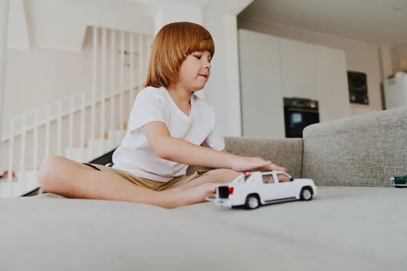 Playful boy enjoying time indoors while playing with toy car, showcasing creativity and joy. A bright and inviting atmosphere enhances the fun experience.
