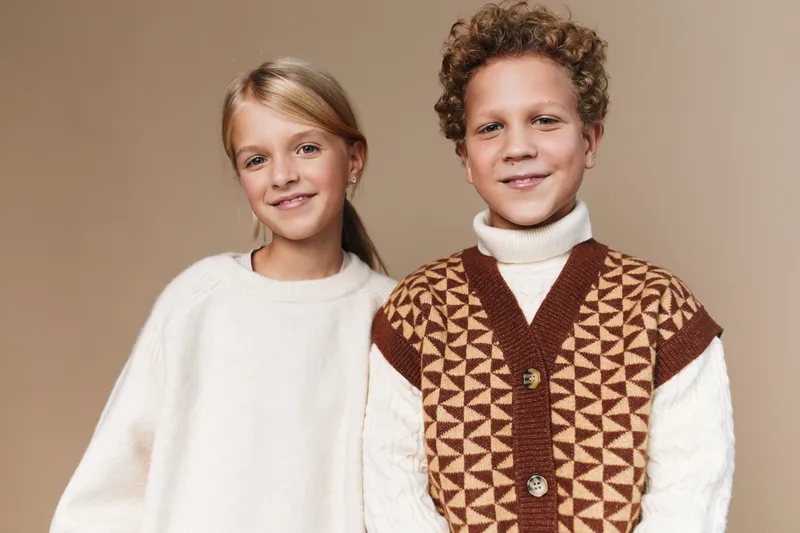Authentic moment of children at play in a warm school setting, a lifestyle portrait capturing genuine smiles, cozy knitwear, and a candid everyday atmosphere.