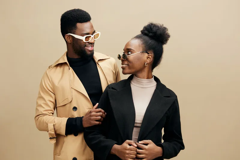 Stylish young couple posing together in trendy outfits, showcasing modern fashion and confidence in a warm toned studio backdrop