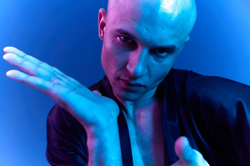 Black and white portrait of a confident man showcasing a dynamic pose with dramatic lighting and high contrast, emphasizing strength and charisma.