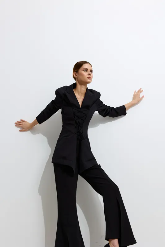 Fashion woman wearing a stylish black outfit poses confidently against a white background, showcasing modern minimalistic beauty and sophisticated urban style.