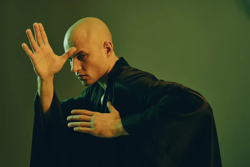 A focused man in a dark kimono striking a martial arts pose, creating a captivating atmosphere with unique lighting and a sense of movement.