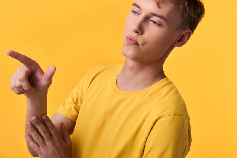 Hand gesture with a pointed finger and a thoughtful gaze in a bright yellow shirt against a vivid yellow backdrop, conveying curiosity, focus, and creative thinking in a modern studio setting