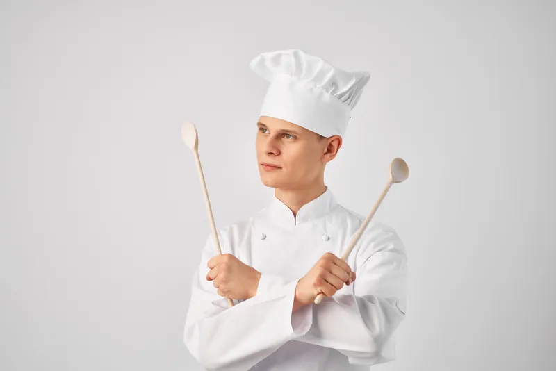 Весёлый шеф-повар-мужчина с кухонной утварью, работающий в ресторане, персонал