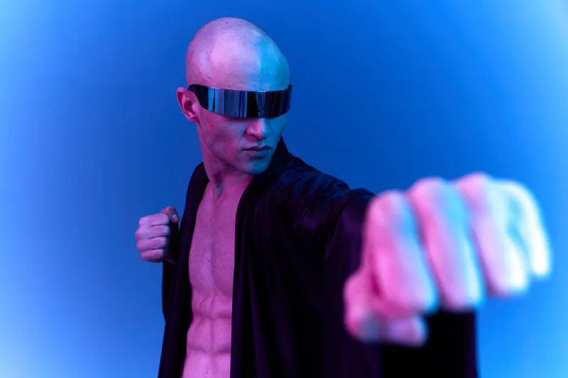 A striking man poses dramatically in a black robe, showcasing his strength and confidence. The vibrant blue and purple lighting adds an energetic vibe to this stunning image.