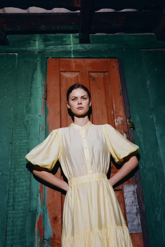 Woman portrait vintage yellow dress confident pose against rustic wooden door authenticity inclusivity in fashion
