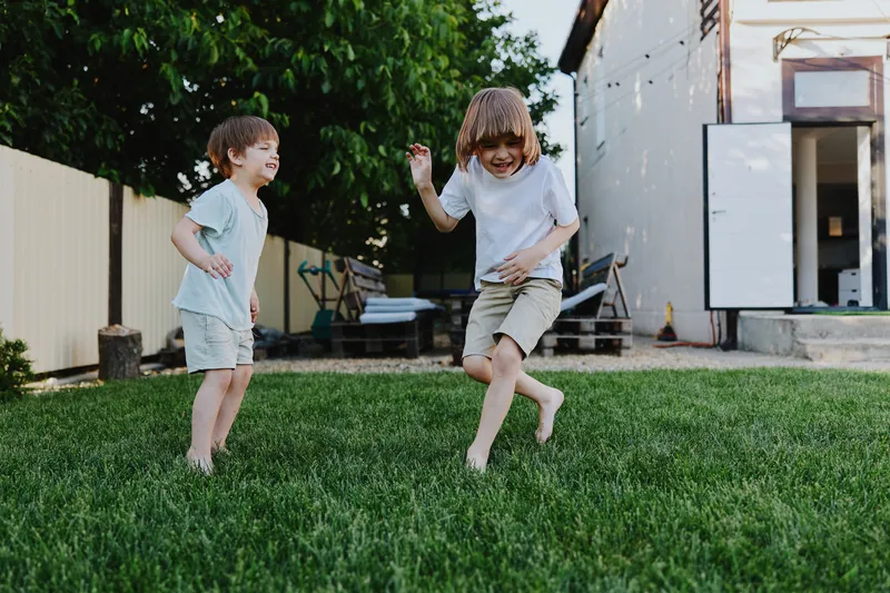 Two joyful boys playing together outdoors, running and laughing on a sunny day. Their carefree spirit captures the essence of childhood fun and happiness.
