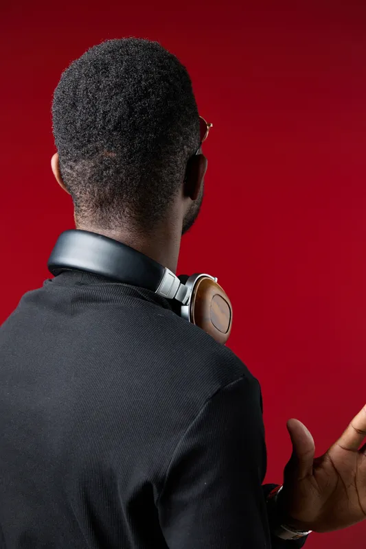 Stylish young man with headphones against a vibrant red background, exuding confidence and modernity while enjoying music