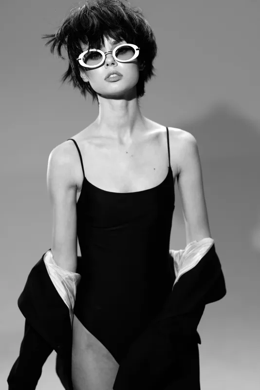 Black and white portrait of a stylish woman wearing sunglasses and a black outfit with confident expression