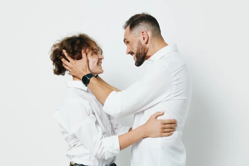A professional man and colleague share a warm moment against a clean white background, showcasing leadership, teamwork, and confidence in a modern business setting.