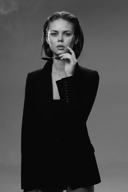 Black and white portrait of a serious woman wearing a dark blazer with wet hair and intense gaze.